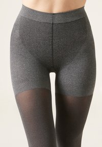 Leggings gris texturé avec une taille lisse, présentant une section inférieure solide et transparente. Le matériau combine des finitions opaques et semi-transparentes.