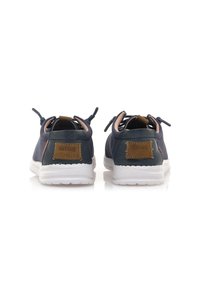 Sneakers blu navy con tomaia in tessuto testurizzato, suola in gomma bianca, dettagli in pelle marrone e linguette sul tallone per un facile indossamento.