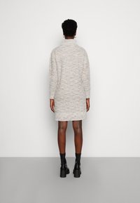 Abito maglione in grigio chiaro, con colletto alto, maniche lunghe e una vestibilità rilassata, impreziosito da leggere screziature multicolori.