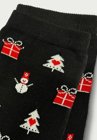 Sorte sokker med røde og hvide julemønstre, herunder snemænd, træer med hjerter og indpakkede gaver.