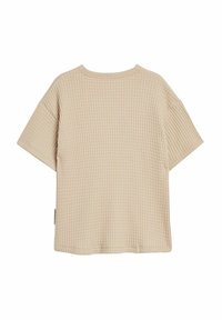 Vaaleanbeige waffle-kudottu lyhythihainen paita, jossa on pyöreä kaula-aukko ja rento leikkaus. Sivusaumassa on pieni etiketti.
