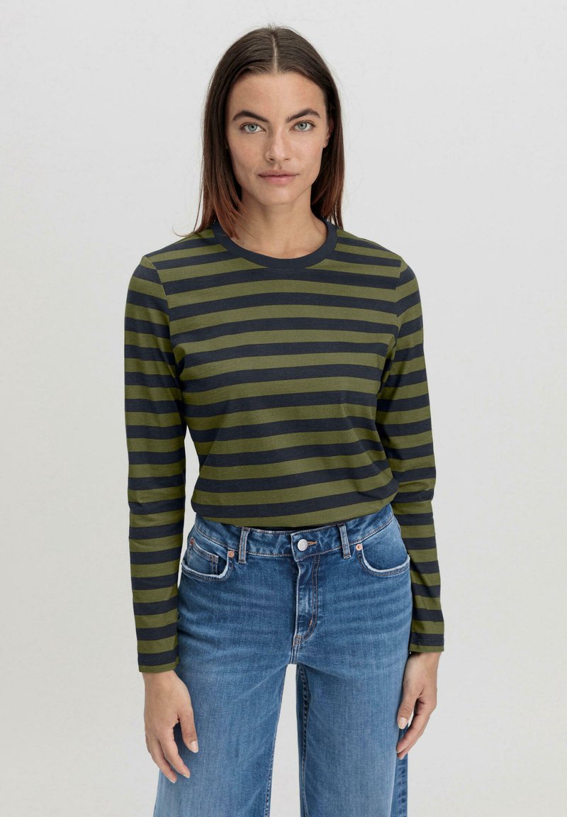 Langärmeliges gestreiftes Hemd in olivgrün und dunkelgrau, mit Rundhalsausschnitt, kombiniert mit hochgeschnittenen blauen Jeans.