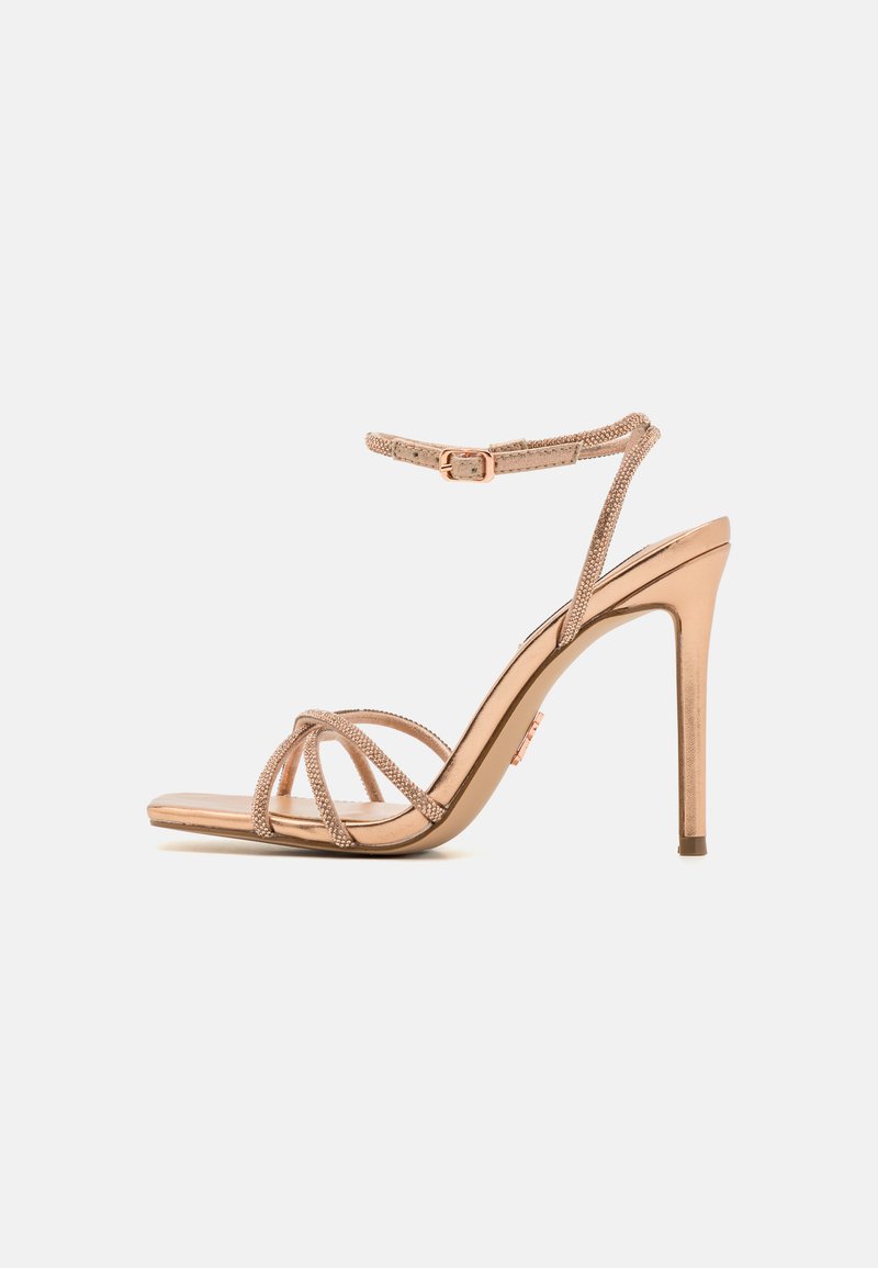 Sandalo con tacco alto e cinghie in oro rosa. Presenta cinghie sottili con una finitura testurizzata, una punta quadrata e un tacco stiletto snodato.