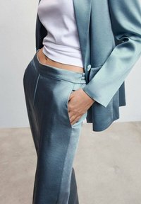 Satinanzugset in Hellblau, bestehend aus einem maßgeschneiderten Blazer mit einem einzelnen Knopf und hochtaillierten Hosen mit Taschen, glatte Textur.