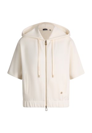 Veste courte crème à manches courtes avec capuche, fermeture éclair à l'avant, cordon de serrage à la capuche, poches latérales et petit badge logo rond près de l'ourlet.