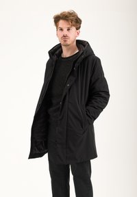 Giacca nera con cappuccio, con chiusura a zip e bottoni automatici, dotata di tasche laterali e texture liscia. Fodera interna in tessuto trapuntato.