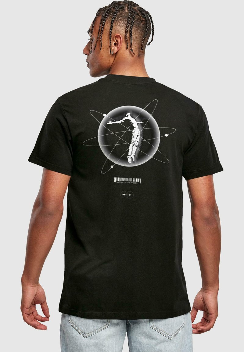 Sort bomulds T-shirt med et grafisk design på ryggen, der viser en astronaut inden i en cirkulær atomillustration med tekst og stregkode.