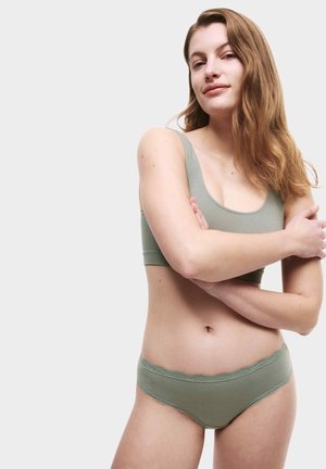 Lichtgroene naadloze bralette en bijpassende slipjes met golvende kanten afwerking, met een gladde textuur en een aansluitend ontwerp.