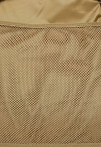 Tan mesh fabric with a diamond pattern and smooth backing. The texture is soft, with a reinforced edge at the top for durability.