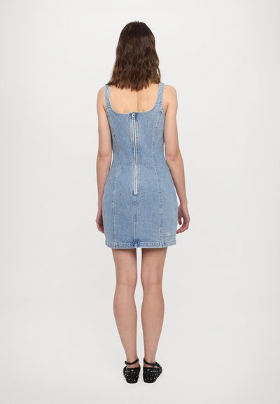 Denim mini kleit reguleeritavate õlavarre rihmadega, tagumise tõmbluku ja veidi laieneva hemiga. Helesinine värv ja sile tekstuur.