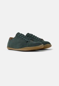 Scarpe in suede verde con punta rotonda, design allacciato e suola in gomma marrone. Superficie liscia con dettagli di cucitura minimi.
