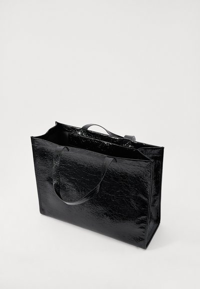 Black, glossy tote bag with a rectangular shape, textured surface, and dual handles. Features embossed text on the front.