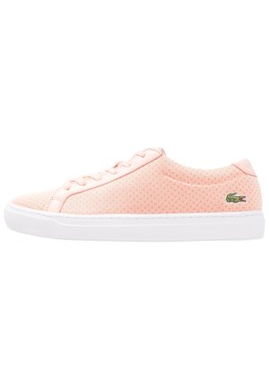 Jasnoróżowy dziergany niskoprofilowy sneaker z białą podeszwą i zielonym logo krokodyla z boku.