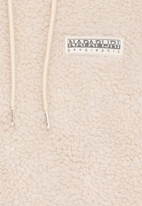 Haut de hoodie en polaire couleur crème avec une surface douce et texturée, doté d'une capuche avec cordons de serrage et d'un patch rectangulaire affichant "NAPAPIJRI geographic."