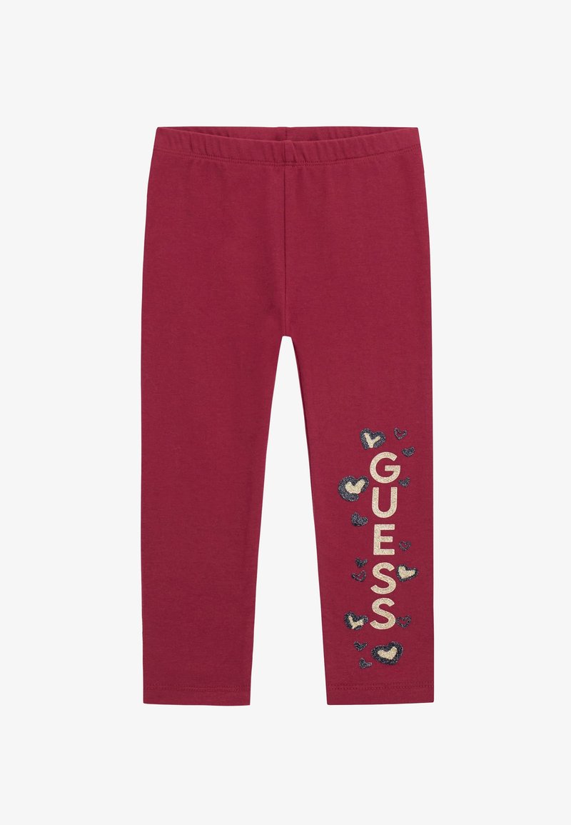 Burgundy leggings with an elastic waistband. "GUESS" logo printed in gold, surrounded by smaller heart shapes in dark blue and cream.
