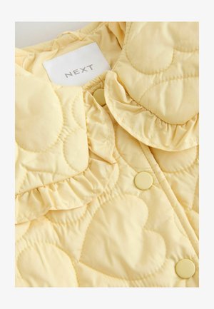 Gelbe gesteppte Jacke mit herzförmigen Mustern, Rüschenausschnitt und passenden Knöpfen. Im Inneren mit dem "NEXT"-Label versehen.