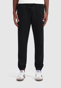 Zwarte sweatpants gemaakt van een katoenmix, met een elastische tailleband met een trekkoord, taps toelopende benen en omgeslagen onderkanten. Past goed bij witte sneakers.