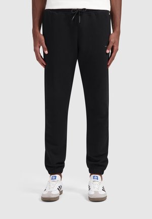 Zwarte sweatpants gemaakt van een katoenmix, met een elastische tailleband met een trekkoord, taps toelopende benen en omgeslagen onderkanten. Past goed bij witte sneakers.