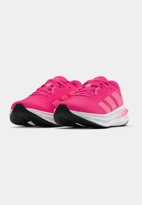 Chaussures de sport rose vif avec une tige en mesh texturé, semelle blanche et semelle extérieure en caoutchouc noir ; elles présentent trois bandes latérales d'un rose plus clair.