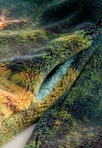 Couverture en polaire avec un dégradé multicolore de teintes vertes, oranges et bleues ; surface douce et texturée avec un revêtement en peluche.