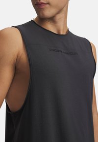 Μαύρο αμάνικο αθλητικό μπλουζάκι από ύφασμα με λεία υφή. Διαθέτει στρογγυλή λαιμόκοψη και το λογότυπο «UNDER ARMOUR» τυπωμένο μπροστά.