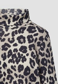 Maglia a maniche lunghe con colletto a dolcevita in tessuto crema con stampa leopardata nera. Texture liscia, vestibilità rilassata e colletto ampio.