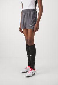 Grå sportshorts med elastisk midjeband, parat med svarta knähöga strumpor med en vit swoosh och vita/röda fotbollsskor.