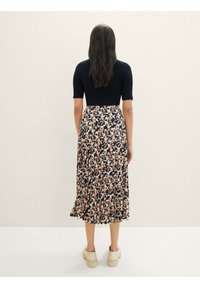 Robe florale avec un haut côtelé marin et une jupe plissée, à hauteur du genou, présentant un imprimé floral pêche et crème sur fond noir.