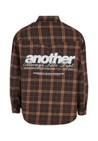 Brown plaid flannel shirt featuring a white graphic text logo on the back. Long sleeves with button cuffs and a rounded hem.