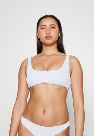 Top de biquíni branco com decote quadrado, alças ajustáveis e detalhe em botão na frente. O material parece suave e texturizado.