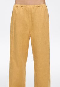 Light yellow linen wide-leg pants with an elastic waistband, featuring a smooth texture and clean seams for a relaxed fit.
