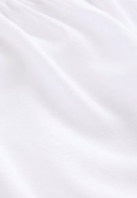 White fabric with a soft, lightweight texture and subtle, woven pattern, displaying gentle folds and smooth surface.