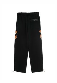 Pantalones de chándal negros con cintura elástica, que presentan acentos bordados en color beige en las piernas y una abertura con cremallera en el tobillo.