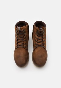 Botas de tobillo de cuero marrón con un acabado texturizado, herrajes de metal y diseño de cordones. Cuentan con un cuello acolchado y cierre de cremallera en el lateral.