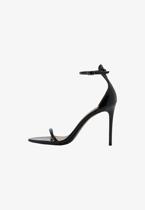 Black high-heeled sandal with a glossy patent finish, thin ankle strap, and minimalist toe strap. Stiletto heel and flat sole.