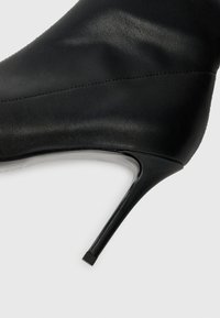 Black high-heeled shoe featuring a smooth leather upper, pointed toe, sleek silhouette, and a narrow stiletto heel with a square base.