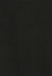 Mörkgrön stickad tyg med en våffelstruktur som visar ett konsekvent rutmönster och mjuka ulliga fibrer.