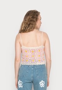 Top em crochet em rosa claro e amarelo com padrões quadrados, apresentando alças finas e um design texturizado.