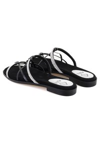 Zwarte sandalen met een suede textuur, voorzien van kruislings banden en zilveren accenten. Platte zool met een subtiele verhoging, elegante ontwerpelementen.