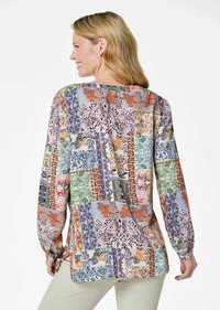 Langärmliges Oberteil mit einem bunten Patchwork-Design und floralen Mustern in Blau, Orange und Grün. Weicher Stoff mit lockerer Passform.