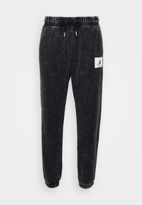 Schwarze Sweatpants mit leicht verblasster Textur, elastischem Bund mit Kordelzug und einem weißen Logo-Patch auf der linken Seite.
