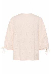 Blusa rosa chiaro con vestibilità ampia, caratterizzata da maniche a sbuffo, tessuto ad occhiello con motivi a diamante e dettagli legati ai polsini.