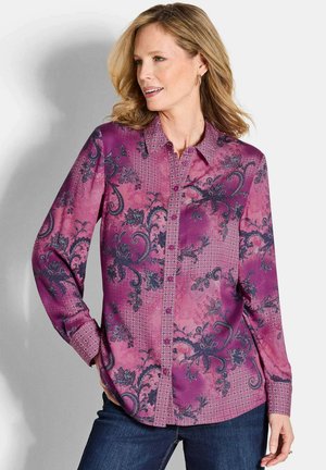 Blouse violet à manches longues avec des motifs floraux et géométriques, col de chemise à boutons et accents texturés subtils.