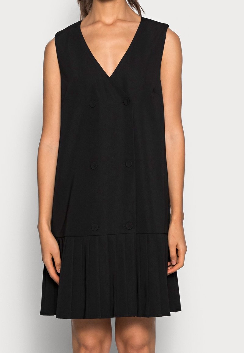 Abito nero senza maniche con scollatura a V, dettaglio di bottoni doppi e gonna plissettata. Tessuto morbido, lunghezza al ginocchio, stile minimale.