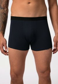 Boxers oscuros de color azul con una tela suave, que presentan una banda elástica negra con la inscripcion "JP1880". Diseño ajustado con una longitud hasta el muslo.