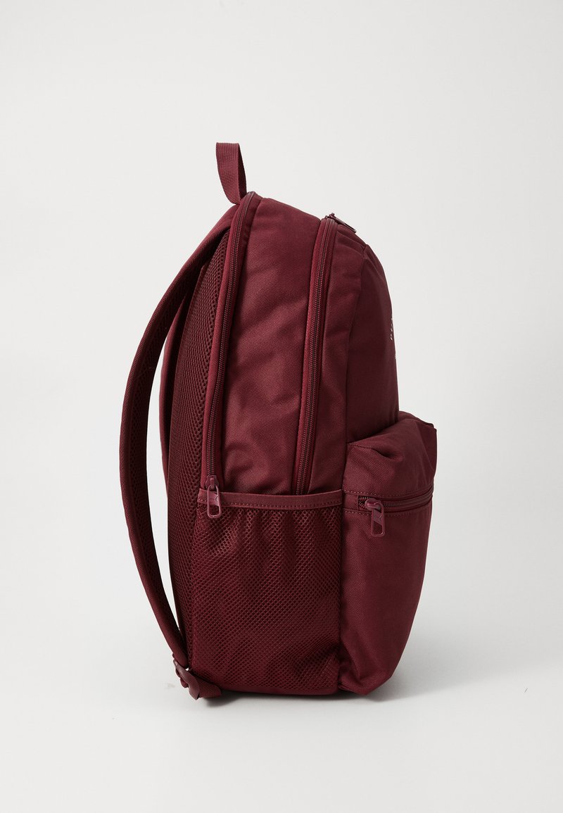 Bordeauxfarbener Rucksack mit zwei Reißverschlussfächern, seitlicher Netzstecktasche, gepolsterten Schulterriemen und einem kleinen Handgriff oben. Hergestellt aus robustem Gewebe mit glatter Textur.
