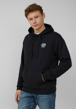 Zwarte hoodie van een katoenmix, met een kangoeroezak, trekkoordkap en een klein turkoois logo op de borst. Draagt met blauwe jeans.