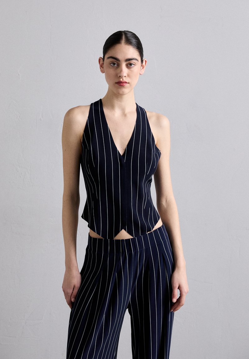 Navy striped sleeveless top with a V-neck and cut-out detail at the waist, paired with matching striped wide-leg pants. Smooth fabric texture.