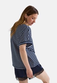 Haut à manches courtes rayé bleu marine et blanc avec une coupe décontractée. Associé à un short sombre avec une finition en dentelle noire.