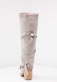 Bottine grise en suède, au-dessus du genou, avec un design de lien enroulé, bout rond et talon en bois empilé. Détails de couture le long de la couture arrière.